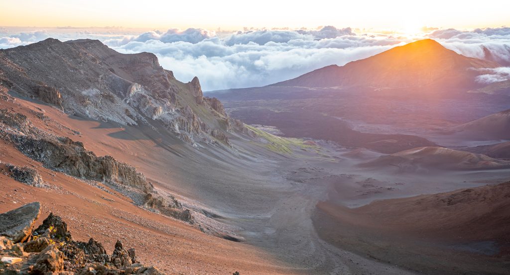 Sweeping view of Haleakalā’s volcanic slopes at golden hour above the clouds in Maui, Hawaii