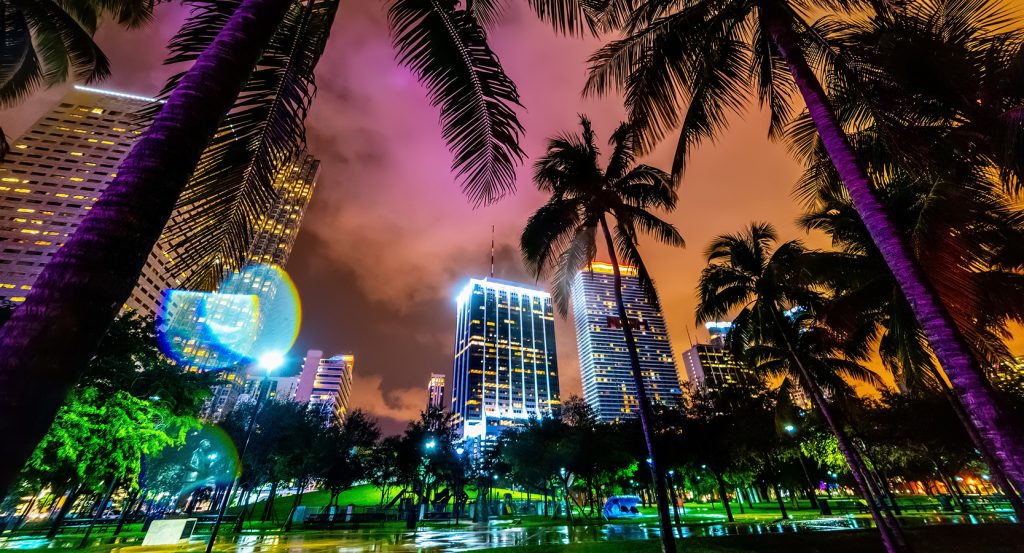 Colorful reflections and skyscrapers under a moody pink and orange Miami sky.