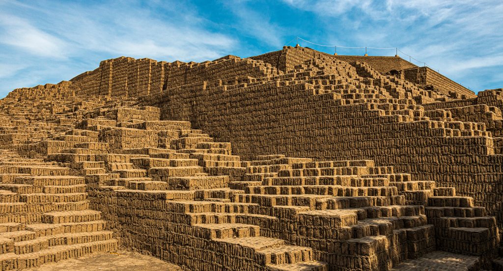 Ancient brick terraces of Huaca Pucllana rise under a vibrant Peruvian sky.