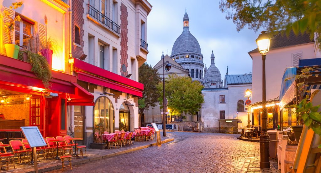Charming Parisian cafés and glowing streetlamps in the early morning near Sacré-Cœur.