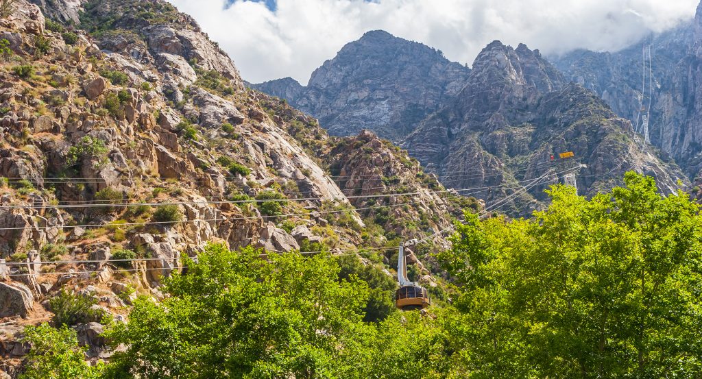 Palm Springs mountain cable car traveling through San Jacinto Canyon with forest below and peaks above.