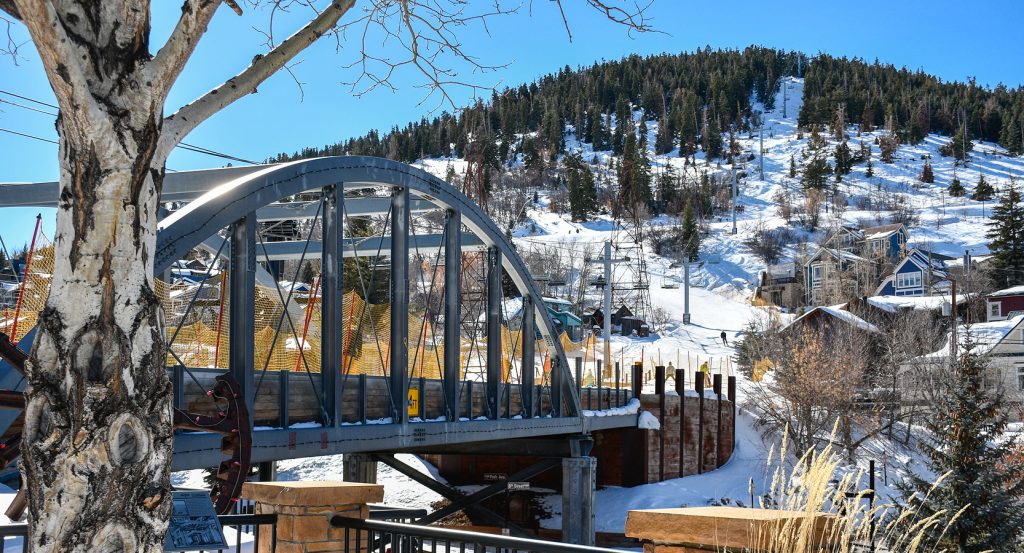 Scenic winter view of Park City featuring a snow-dusted bridge and mountain homes nestled on a hillside.