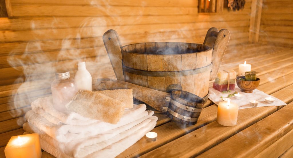 Cozy sauna setup in Helsinki featuring candles, towels, and birchwood decor.