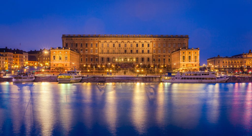Evening view of the Royal Palace in Stockholm with boats docked along the shore.