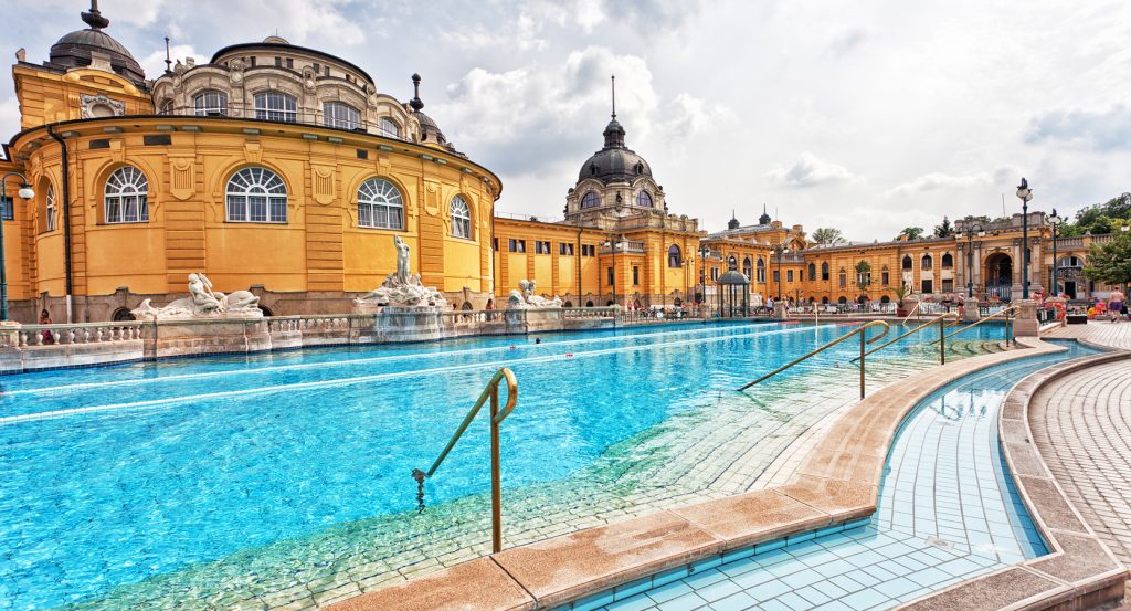 View of Budapest’s historic thermal spa with blue pool waters and ornate architecture.