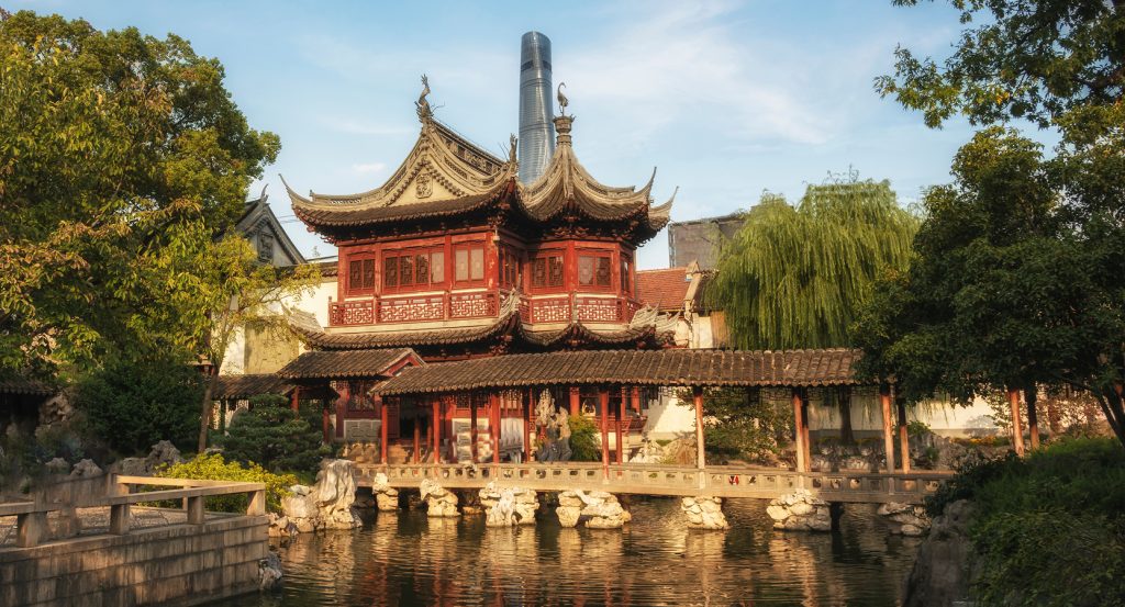 Classic Chinese pavilion framed by lush trees and golden light in Shanghai’s Old City