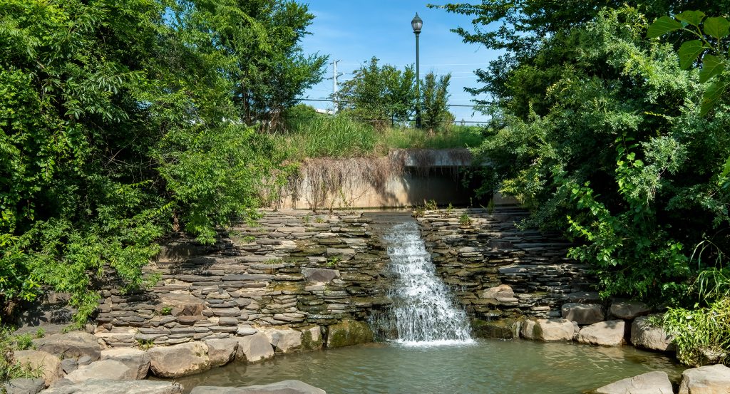 Peaceful urban stream with stone waterfall framed by lush trees in Charlotte, NC