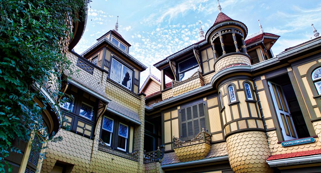 Architectural close-up of the Victorian-style Winchester Mystery House against a bright sky.