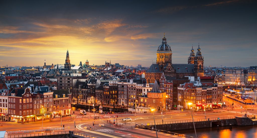 Cityscape of Amsterdam at dusk featuring the Basilica of Saint Nicholas