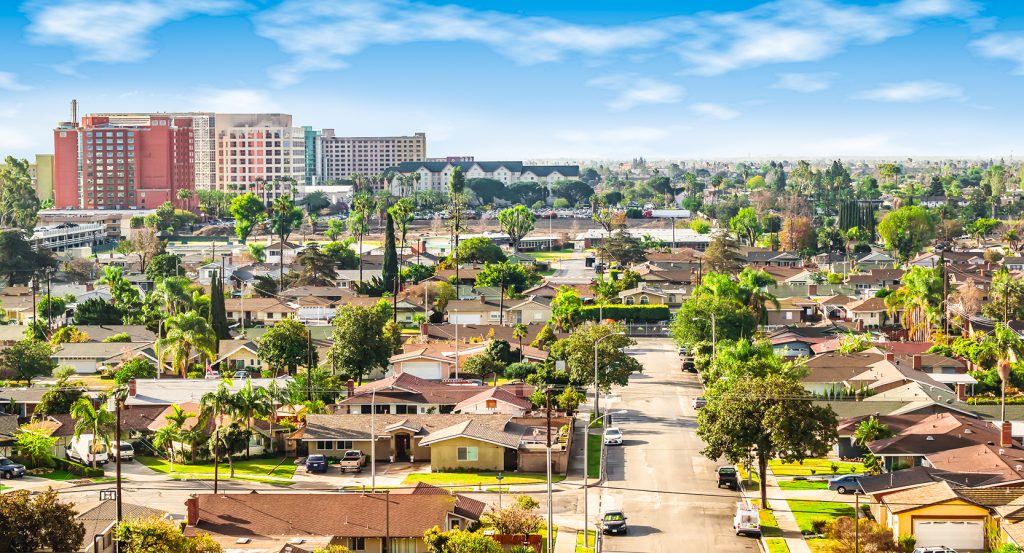 Vibrant sunset casting golden hues over modern buildings and lush greenery in Anaheim, California.