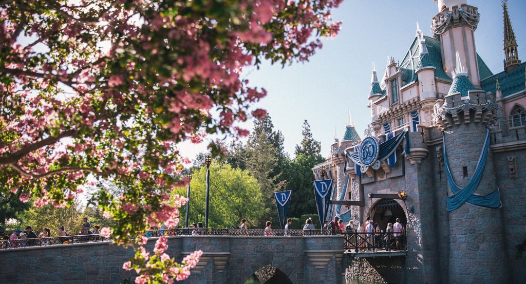 Sleeping Beauty Castle at Disneyland peeking through springtime blossoms, capturing the magic of Anaheim’s most iconic landmark.