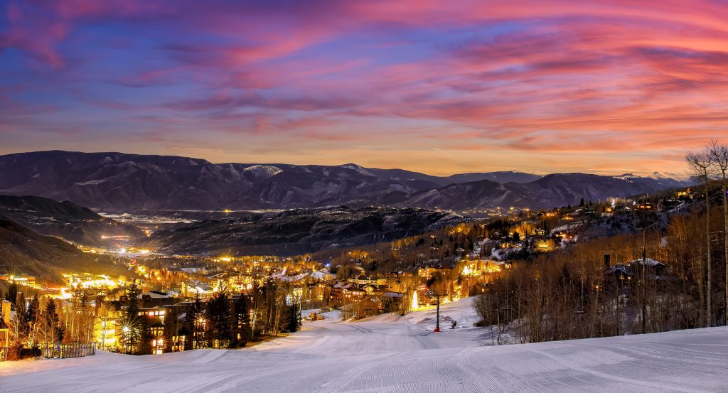Alpenglow sky above a snowy slope and illuminated alpine town in Colorado