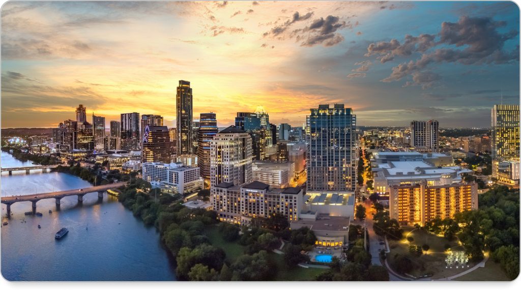 Kayakers float along Lady Bird Lake with the Austin skyline rising behind them at golden hour.
