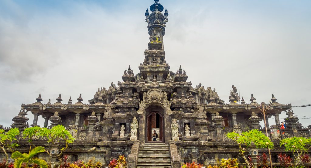 Balinese temple entrance framed by tropical greenery and cloudy skies
