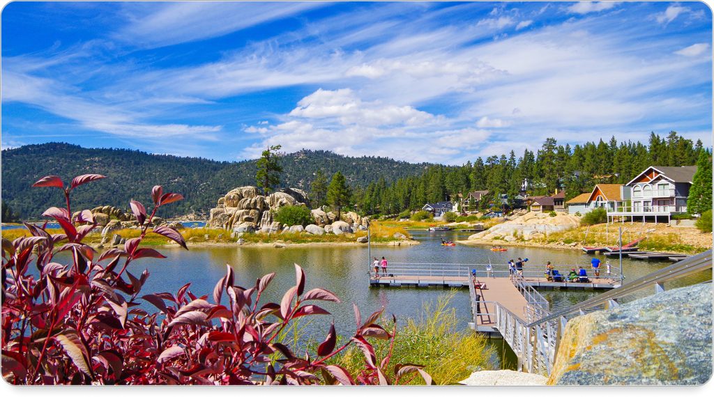 Kayakers gliding across the calm blue waters of Big Bear Lake with mountain peaks in the background.
