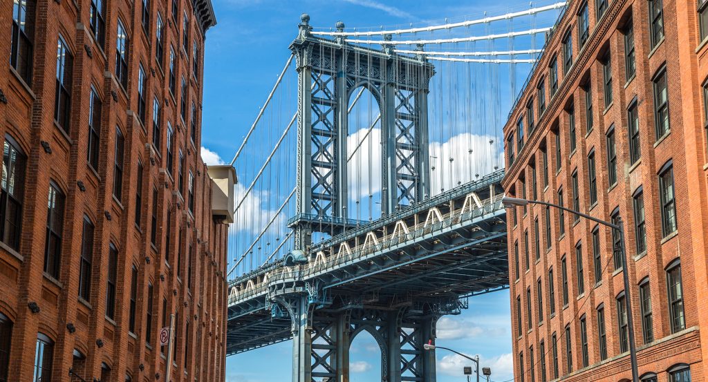 The Manhattan Bridge framed by red-brick warehouses in Brooklyn’s DUMBO neighborhood, a perfect blend of history and hip.