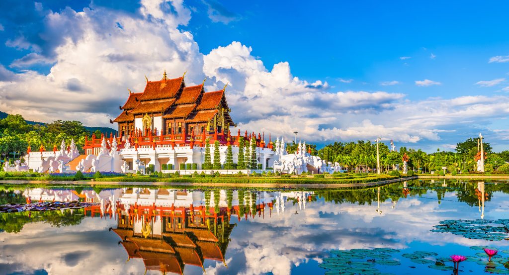 Chiang Mai’s royal pavilion surrounded by manicured grounds and dramatic clouds mirrored on a peaceful lake.