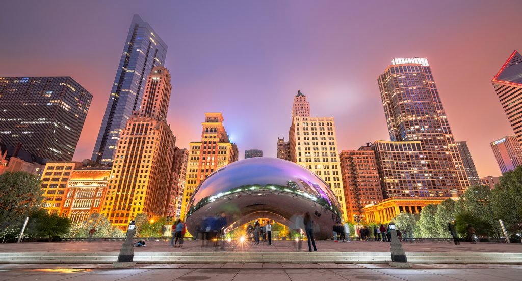 Evening view of Chicago’s skyline with the iconic Bean sculpture and glowing skyscrapers.