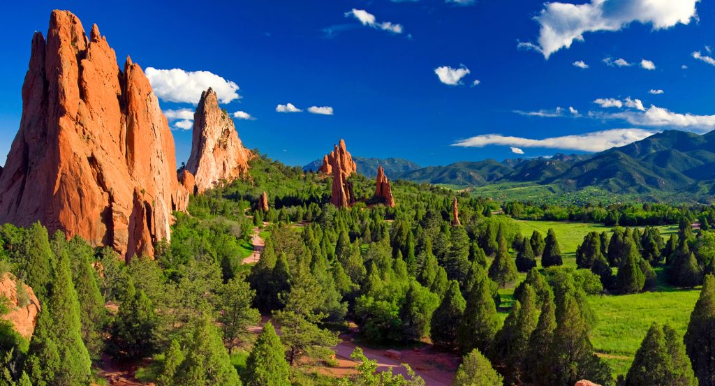Jagged sandstone spires and pine trees under a vivid sunset in Colorado Springs, Colorado