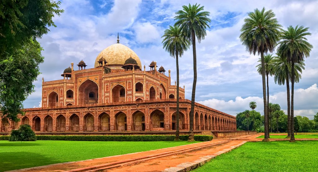 Historic Mughal architecture of Humayun’s Tomb under a partly cloudy sky in India.