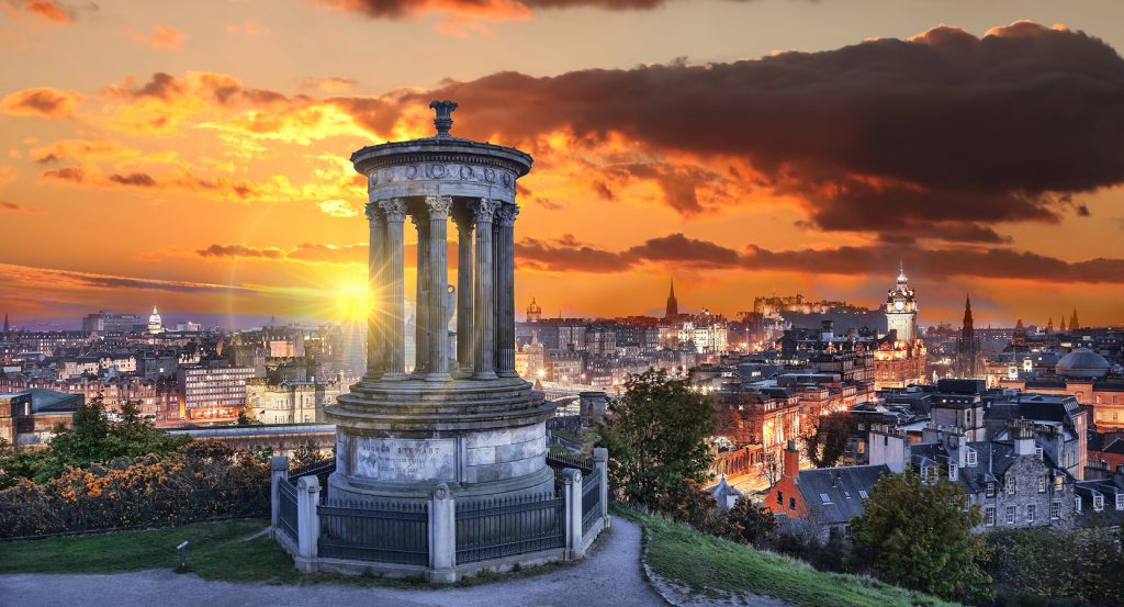 Calton Hill at golden hour, overlooking Edinburgh’s skyline with the Dugald Stewart Monument in silhouette.