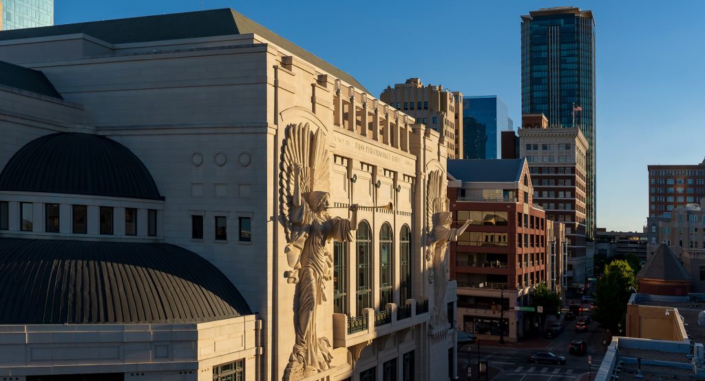 Ornate facade of Bass Performance Hall in downtown Fort Worth, surrounded by city skyline.