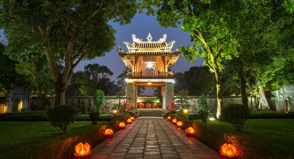 Pathway lined with lanterns leading to the illuminated Temple of Literature in Hanoi, Vietnam at night.