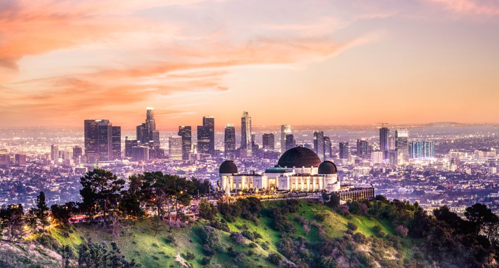 The sun sets behind the Los Angeles skyline as the Griffith Observatory glows on the hilltop, overlooking the city lights of Hollywood.