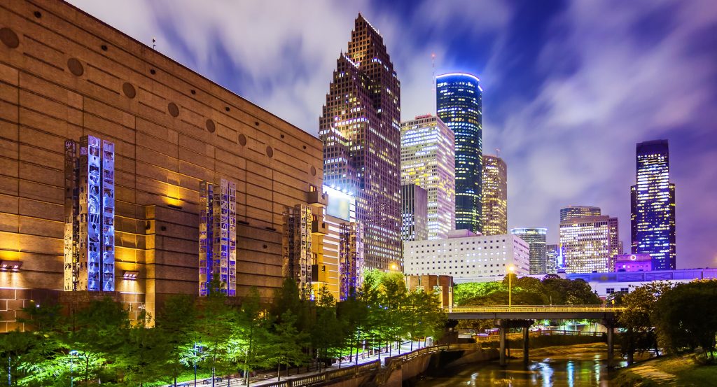 Downtown Houston cityscape featuring brightly lit skyscrapers and the theater district at dusk