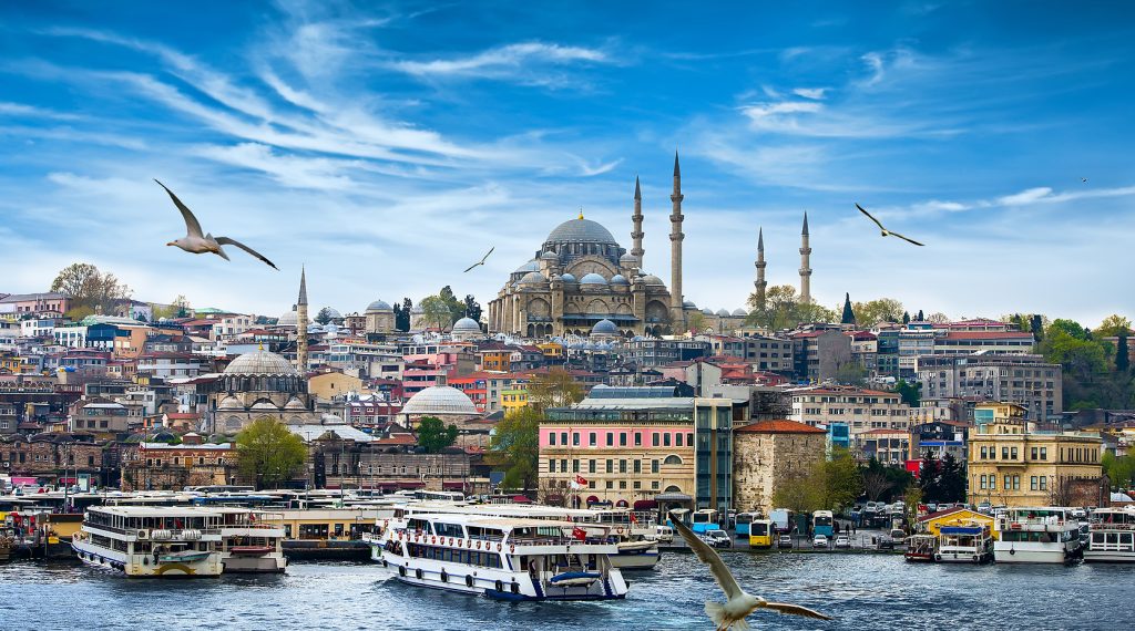 View of Istanbul’s mosques and domes with ferries gliding across the Bosphorus under a blue sky