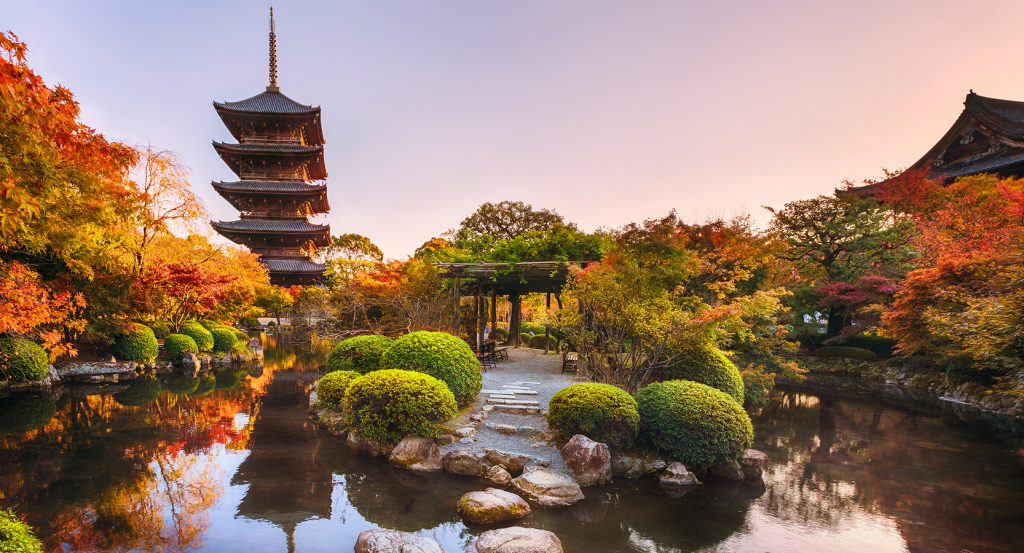 Reflections of colorful trees and historic architecture in a peaceful Kyoto temple garden.