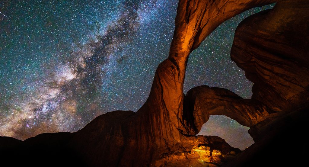 Milky Way galaxy shining above natural sandstone arches in Moab.
