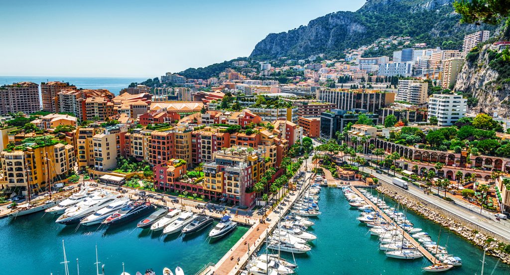A vibrant hillside of pastel buildings cascading down to Port Hercules, where mega-yachts shimmer against Monte Carlo’s famed Mediterranean coastline.