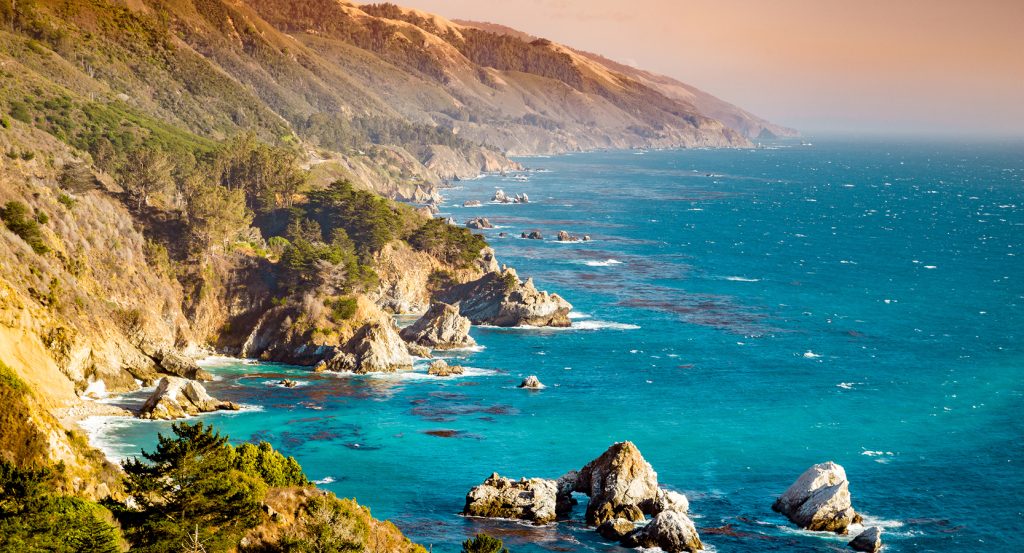 Rugged cliffs meet turquoise waves along the Monterey coastline, where wild beauty hugs the Pacific in dramatic, camera-ready style.