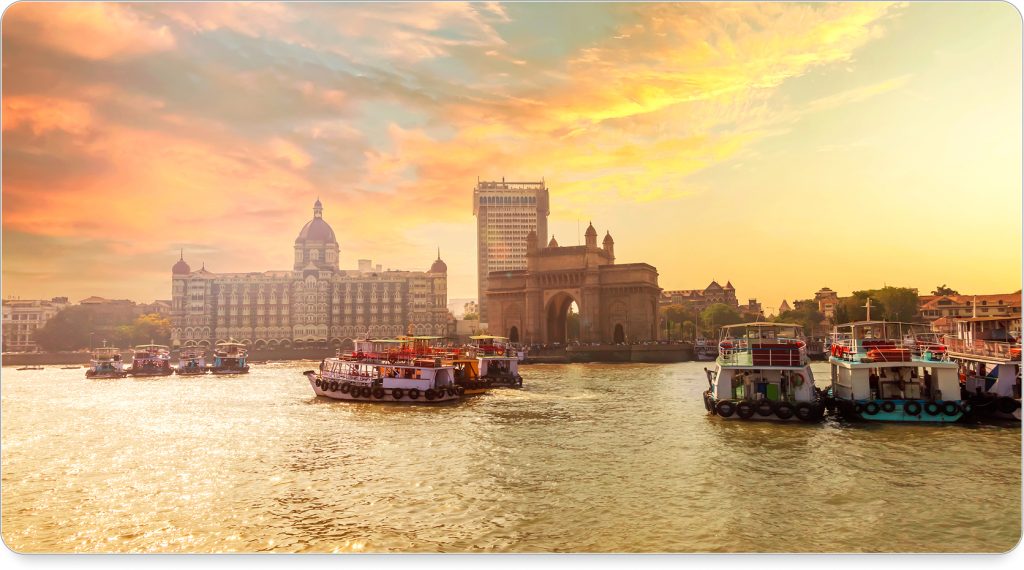 A bustling Mumbai street lined with colorful market stalls and tuk-tuks weaving through the crowd.