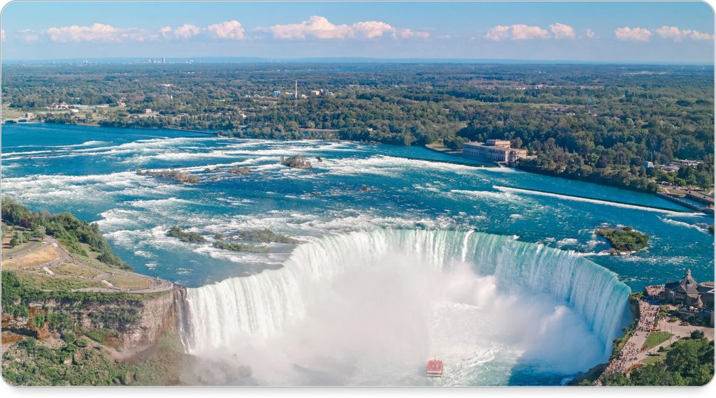 Tourists on a boat in bright ponchos approaching the thundering base of Niagara Falls.