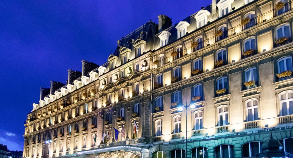 Grand Haussmann-style hotel lit at dusk in central Paris