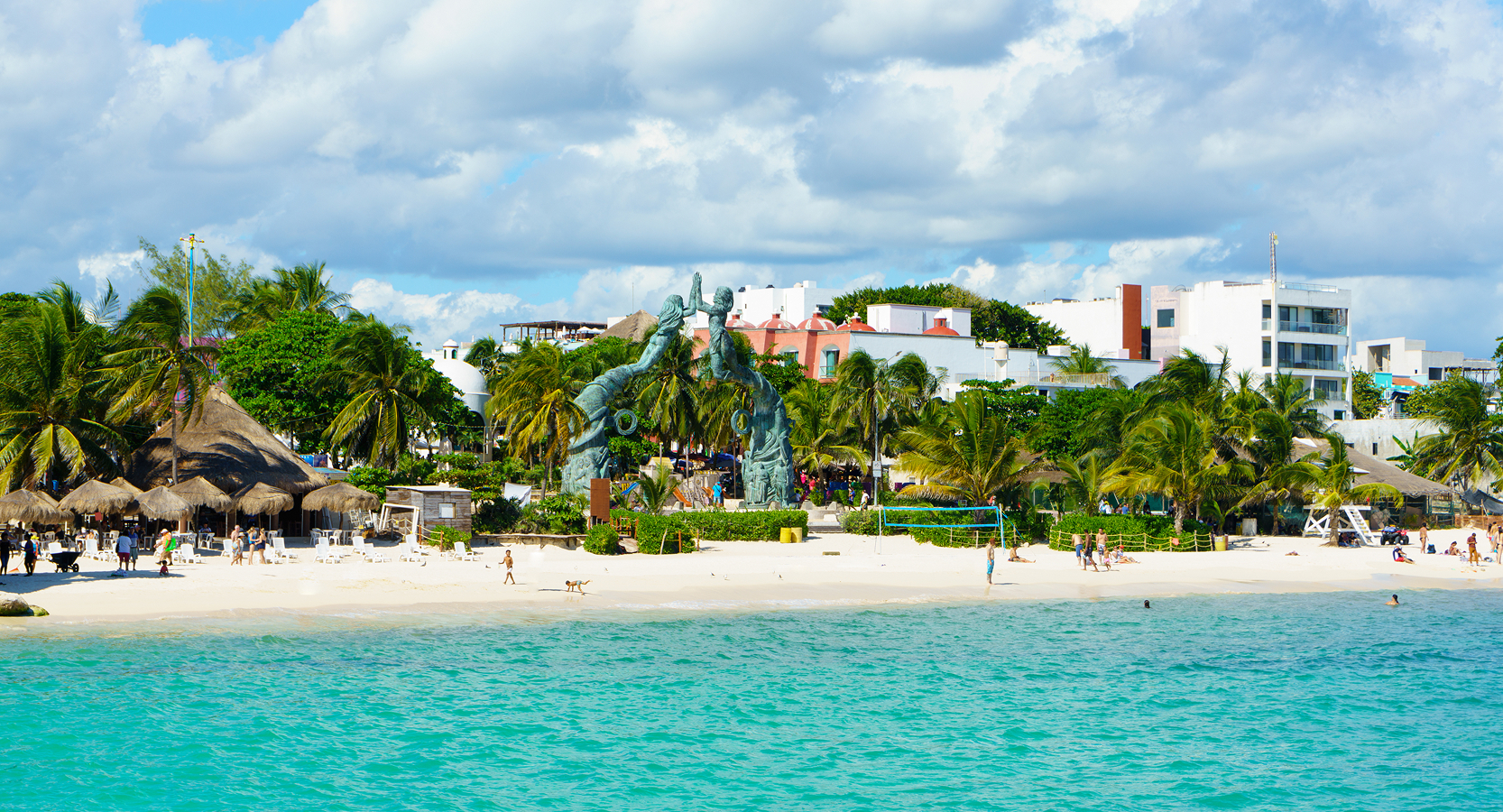 Vibrant coastal scene in Playa del Carmen featuring white sand beaches, lush greenery, and beachgoers enjoying the sun.