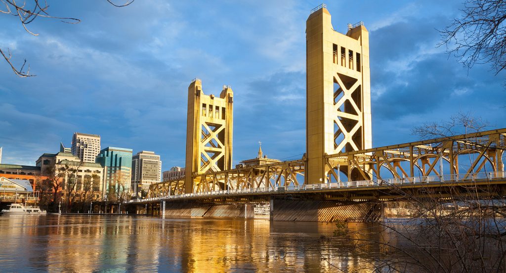 The Tower Bridge gleams gold over the Sacramento River, linking the city’s skyline with Old Sacramento’s rustic charm.