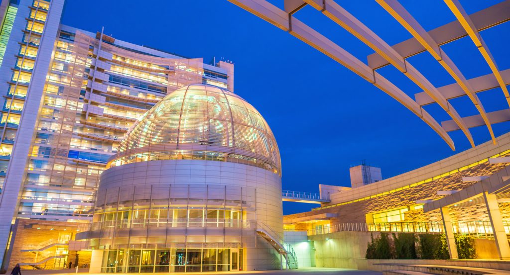 Modern architecture of San Jose City Hall illuminated against a vibrant blue evening sky.