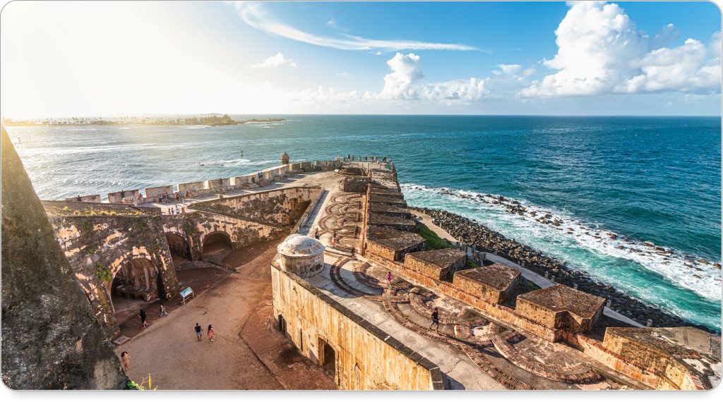 Aerial view of San Juan’s coastline with El Morro fortress perched above the turquoise sea.