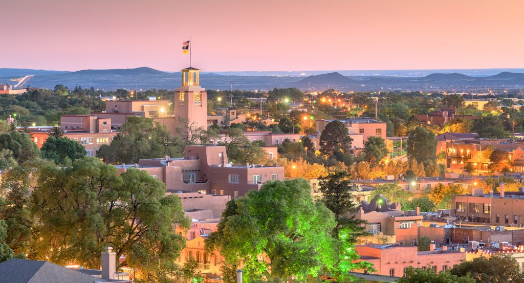 Sunset casts a warm glow on Santa Fe’s low-slung architecture, framed by distant desert mountains.