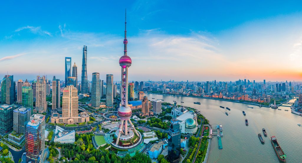 Aerial view of Shanghai at dusk showcasing futuristic skyscrapers and river traffic.