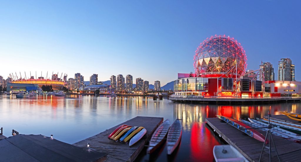 Colorful reflections on the water at dusk in Vancouver, featuring the illuminated geodesic dome of Science World.