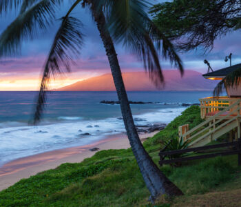 Oceanfront cottage and palm trees at sunset in Kihei, Maui