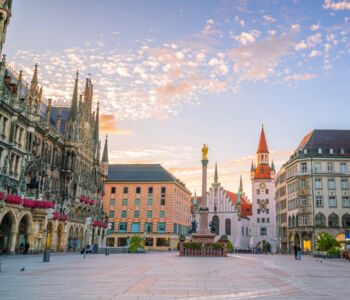 Marienplatz square in Munich with historic buildings and Marian Column at sunset.