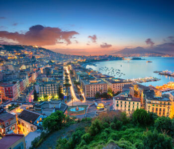 Panoramic view of Naples coastline at twilight with Mount Vesuvius in the distance