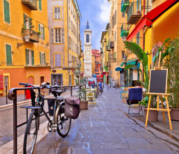 Colorful pedestrian street lined with bikes, cafés, and pastel buildings in a European-style neighborhood.