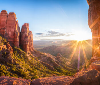 Sunrise over Sedona’s red rock formations and lush valley below.