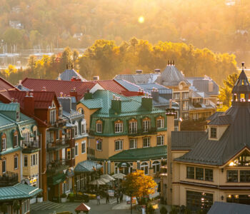 Aerial view of Mont-Tremblant village with colorful rooftops nestled against lush green mountains.